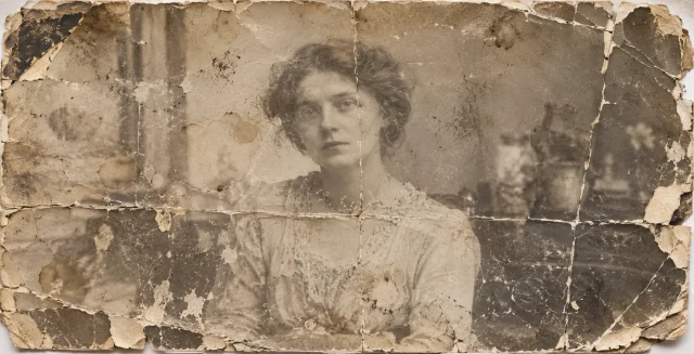 Before restoration: an old sepia portrait of a woman with scratches, creases, damage and fading